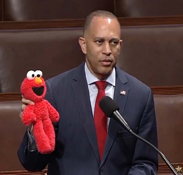 A photo of Hakeem Jeffries in Congress holding an Elmo doll.